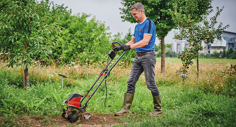 man working in the garden with electric tiller